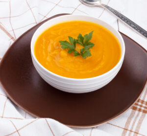 Pumpkin soup in a bowl on white wooden table